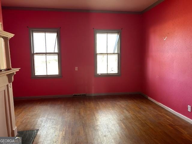 empty room with dark hardwood / wood-style floors, crown molding, and a premium fireplace