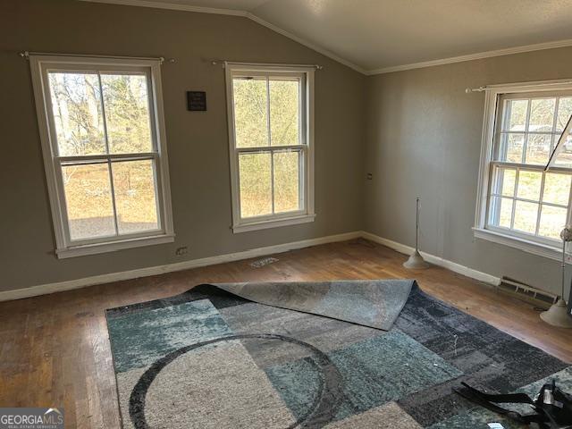 spare room featuring wood-type flooring, crown molding, and vaulted ceiling