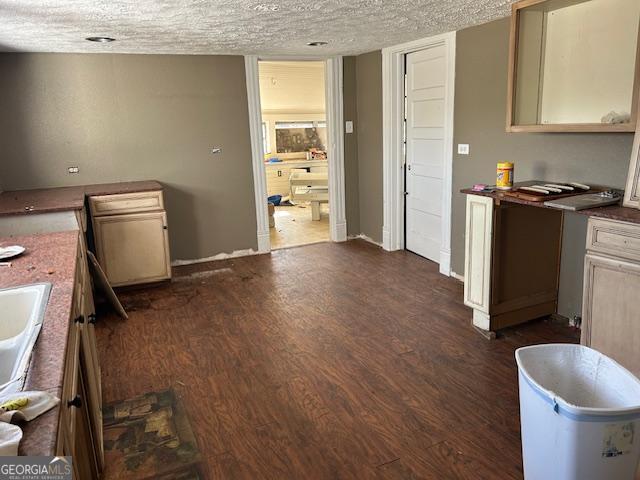 kitchen with cream cabinetry, dark wood-type flooring, and a textured ceiling