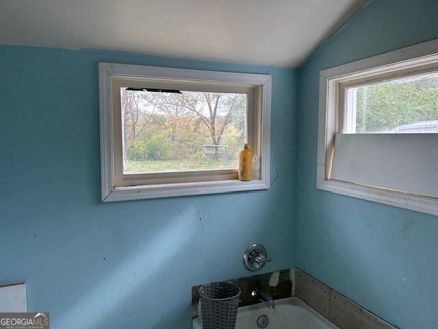 bathroom with a tub to relax in and lofted ceiling