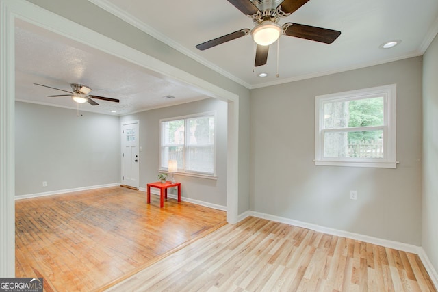 empty room with crown molding, ceiling fan, light hardwood / wood-style floors, and a wealth of natural light