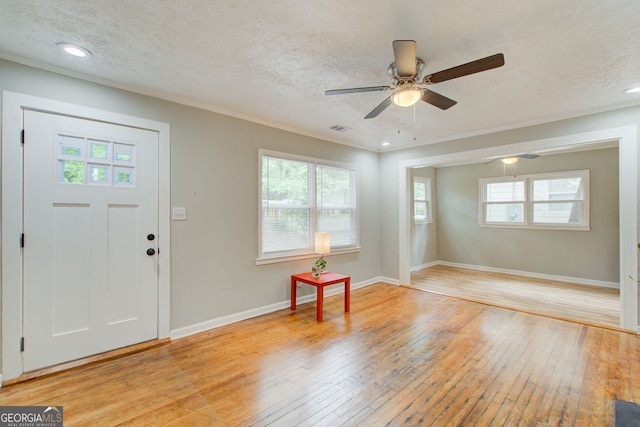 foyer entrance with ceiling fan, light hardwood / wood-style floors, and a textured ceiling