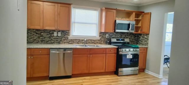 kitchen featuring sink, crown molding, light wood-type flooring, appliances with stainless steel finishes, and backsplash