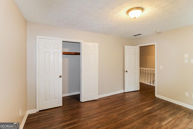 unfurnished bedroom with visible vents, dark wood-type flooring, and baseboards