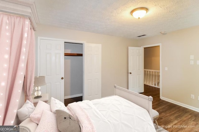 bedroom with dark wood-style floors, baseboards, and a textured ceiling