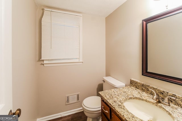 bathroom featuring visible vents, toilet, vanity, and baseboards