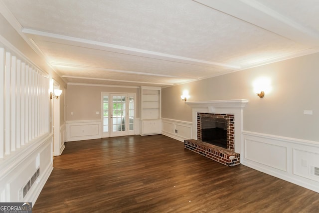 unfurnished living room featuring a brick fireplace, crown molding, french doors, wood finished floors, and a decorative wall