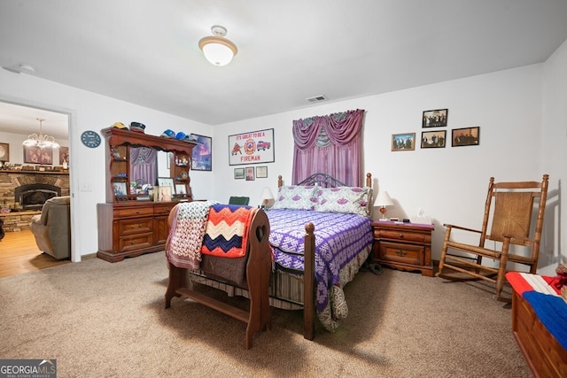 carpeted bedroom featuring a chandelier and a fireplace