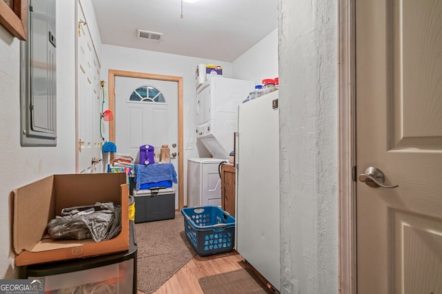 washroom with light hardwood / wood-style floors and stacked washer / drying machine