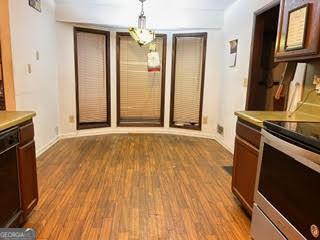 kitchen with black dishwasher, pendant lighting, electric range, and light hardwood / wood-style flooring