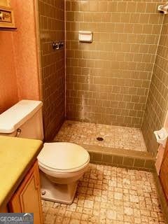 bathroom with tiled shower, vanity, and toilet