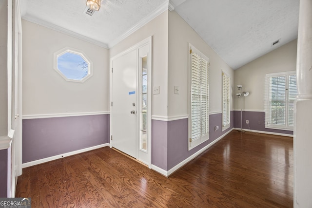 foyer entrance featuring lofted ceiling, a textured ceiling, wood finished floors, and visible vents