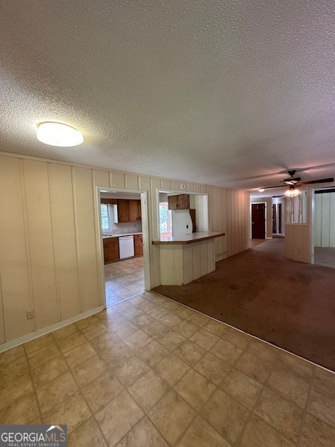 empty room with light carpet, a textured ceiling, and ceiling fan