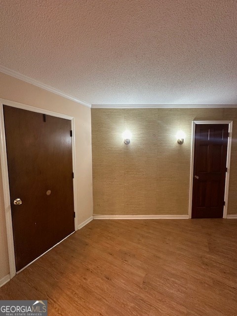 empty room with crown molding, a textured ceiling, and hardwood / wood-style floors