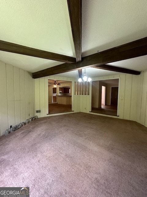 empty room with beamed ceiling, ceiling fan with notable chandelier, a textured ceiling, and carpet flooring