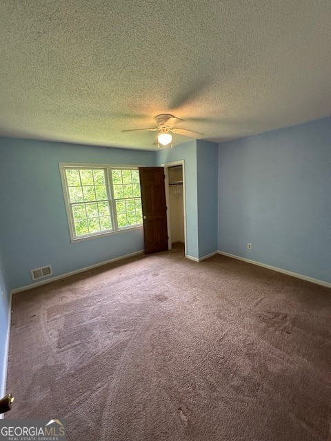 carpeted empty room featuring ceiling fan and a textured ceiling