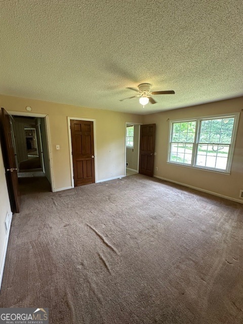 empty room featuring ceiling fan, a textured ceiling, and carpet flooring