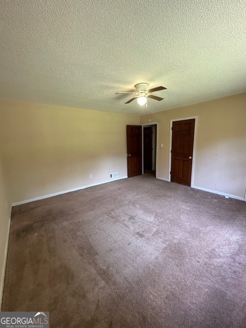 empty room featuring a textured ceiling, carpet floors, and ceiling fan