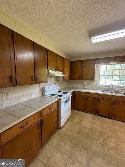 kitchen with a textured ceiling, white electric range, tile countertops, sink, and light tile floors