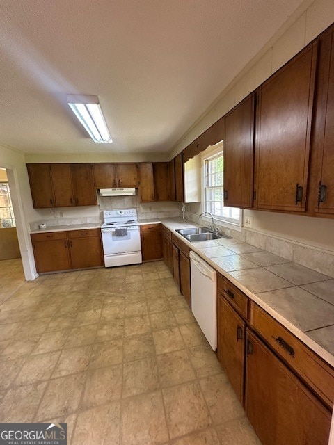 kitchen featuring light tile flooring, tile counters, sink, white appliances, and a textured ceiling