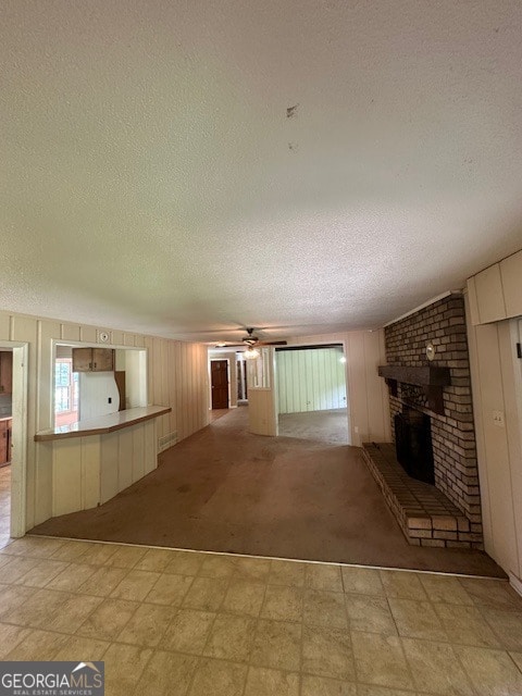 unfurnished living room featuring brick wall, a textured ceiling, light tile flooring, and a fireplace