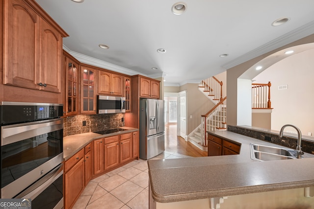 kitchen featuring appliances with stainless steel finishes, kitchen peninsula, backsplash, sink, and light tile floors