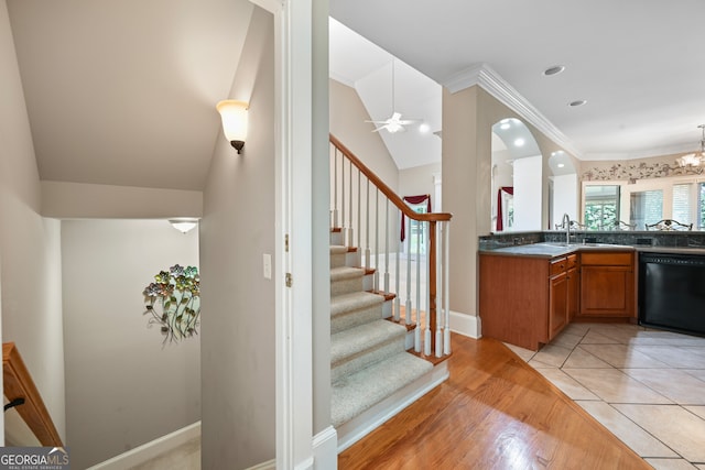 interior space featuring light tile flooring, ceiling fan with notable chandelier, ornamental molding, lofted ceiling, and sink