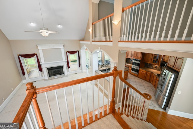 stairway featuring high vaulted ceiling, a wealth of natural light, ceiling fan, and light hardwood / wood-style flooring