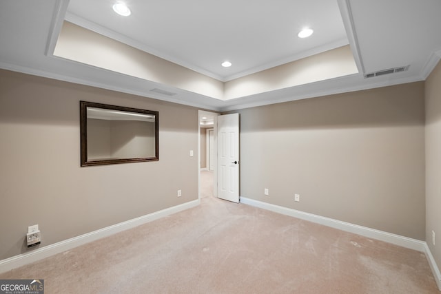 spare room featuring carpet, ornamental molding, and a tray ceiling