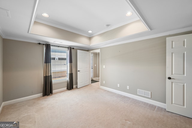 empty room with light colored carpet, ornamental molding, and a tray ceiling