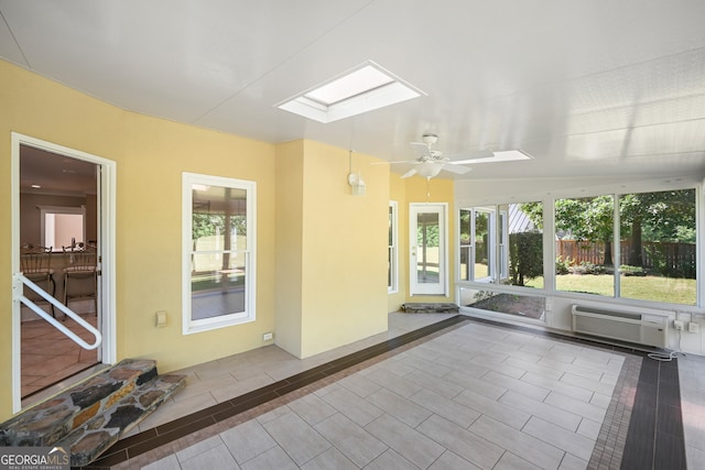 unfurnished sunroom with a wall unit AC, ceiling fan, and a skylight