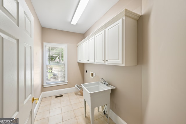 laundry room featuring electric dryer hookup, cabinets, and light tile floors