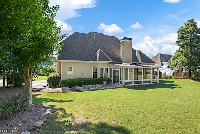 rear view of house featuring a sunroom and a lawn