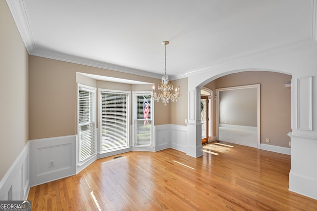 unfurnished dining area featuring a chandelier, light hardwood / wood-style flooring, and crown molding