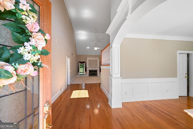 hall with decorative columns, ornamental molding, and wood-type flooring