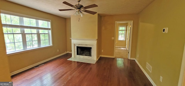 unfurnished living room with ceiling fan, a high end fireplace, a textured ceiling, and dark wood-type flooring