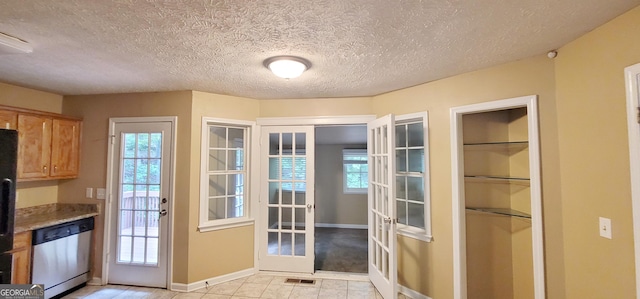 kitchen featuring a wealth of natural light, stainless steel dishwasher, french doors, and light stone countertops