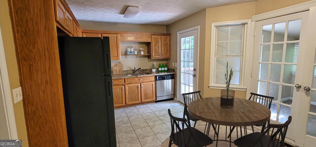 kitchen featuring black fridge, stainless steel dishwasher, light tile patterned flooring, sink, and a textured ceiling