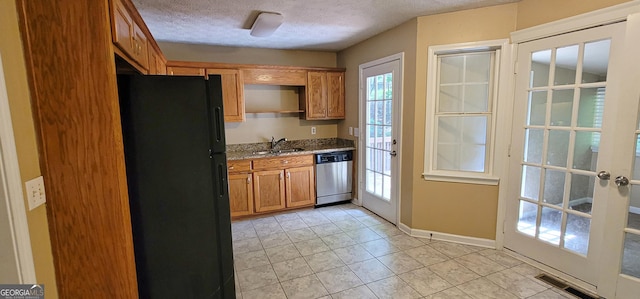 kitchen featuring black refrigerator, french doors, a textured ceiling, stainless steel dishwasher, and sink