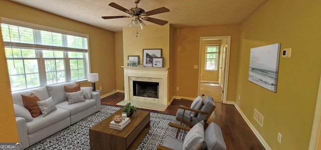 living room featuring a textured ceiling, ceiling fan, dark hardwood / wood-style flooring, and a fireplace