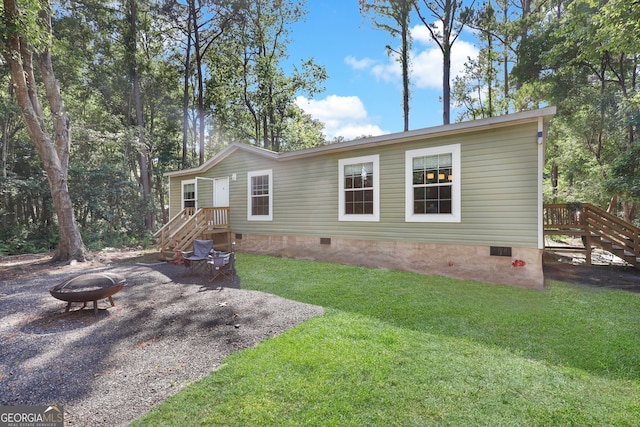 exterior space featuring an outdoor fire pit and a yard