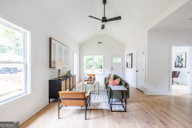 living area with ceiling fan, vaulted ceiling, and light hardwood / wood-style flooring