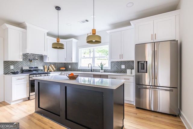 kitchen featuring light hardwood / wood-style floors, a kitchen island, appliances with stainless steel finishes, backsplash, and pendant lighting