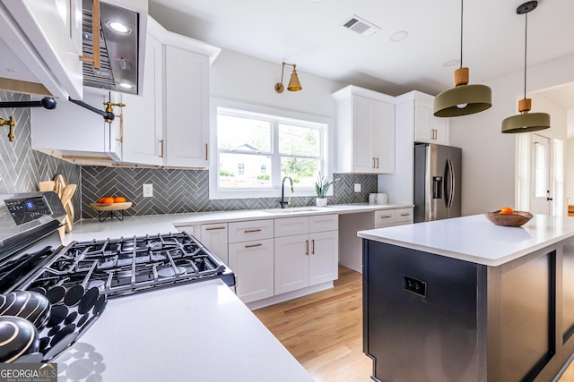 kitchen featuring appliances with stainless steel finishes, white cabinetry, backsplash, and light hardwood / wood-style flooring