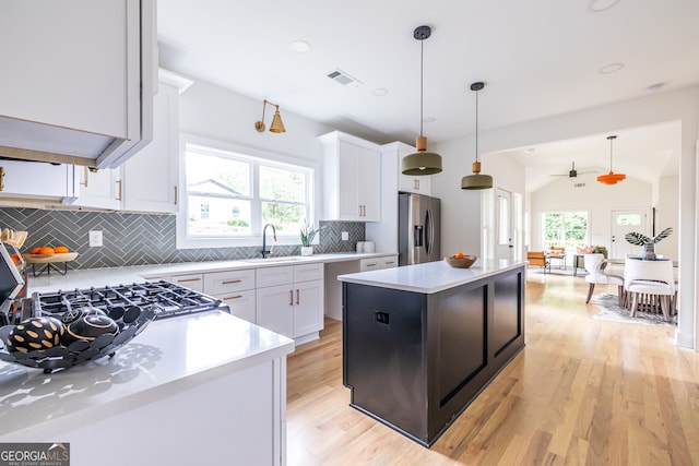 kitchen with hanging light fixtures, light hardwood / wood-style flooring, backsplash, and stainless steel fridge with ice dispenser