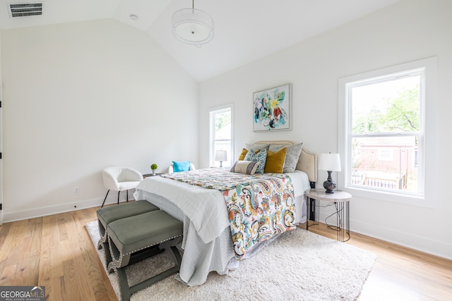 bedroom with lofted ceiling, multiple windows, and hardwood / wood-style floors