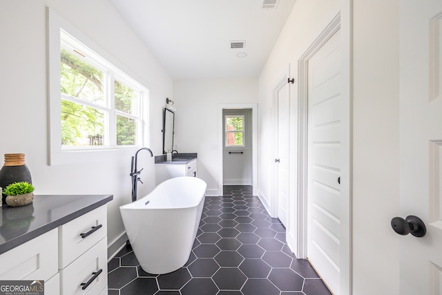 bathroom featuring a washtub, tile flooring, and vanity