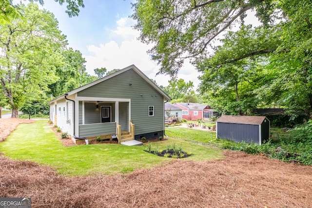 back of house with a yard and a storage unit