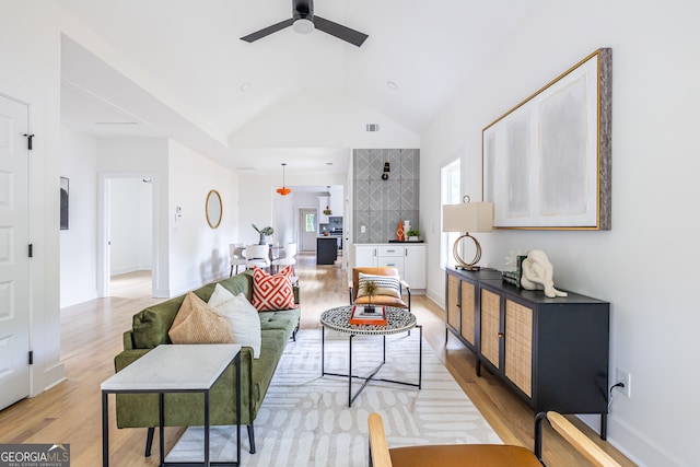 living room featuring light wood-type flooring, vaulted ceiling, and ceiling fan