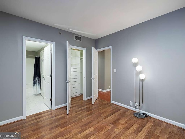 unfurnished bedroom featuring wood-type flooring and connected bathroom